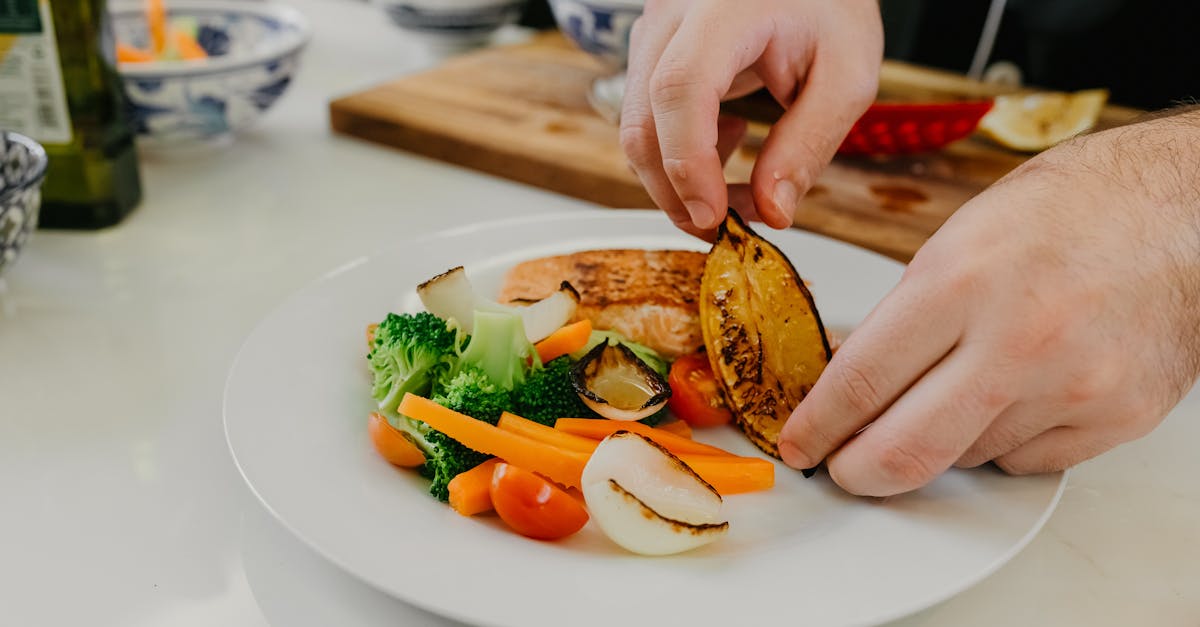 A hand holding a smartphone over a plate of food, logging a meal in a nutrition app